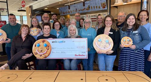 Group of people at Tim Hortons holding a cheque